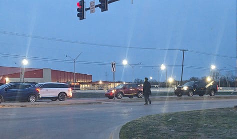 A van approaches a man crossing an intersection