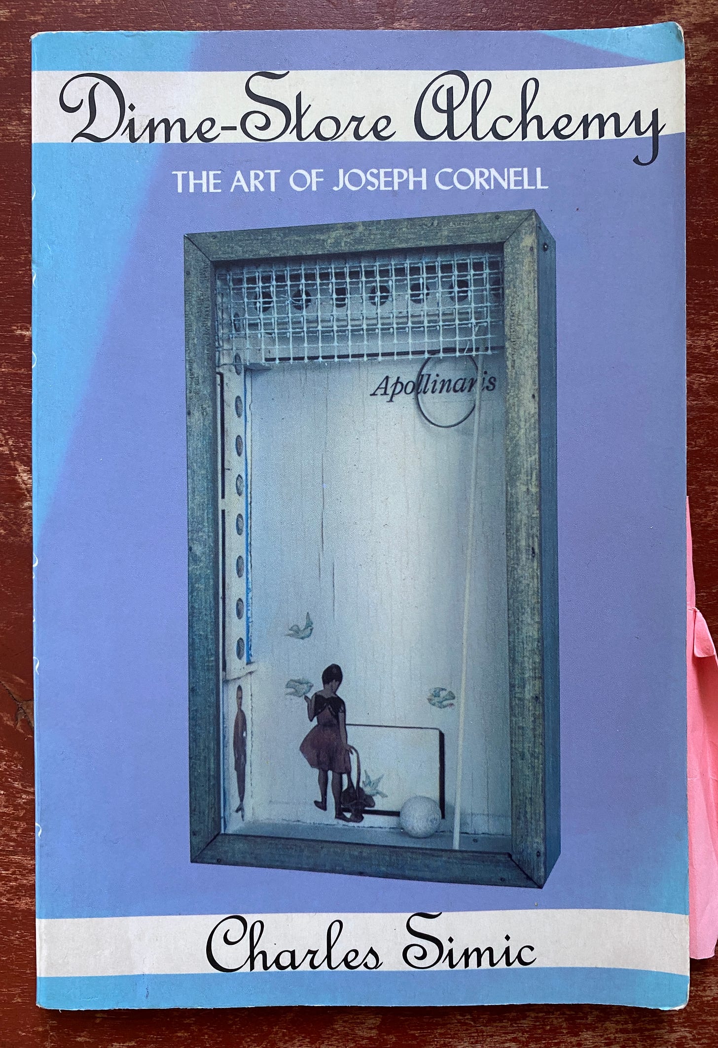  The cover of the Ecco Press edition of Dime-Store Alchemy by Charles Simic. The cover is mostly lavender, with blue fade marks at the coners. It shows a work of art by Joseph Cornell, a shadow box with a cutout illustration of a girl carrying a basket with several white birds fluttering around. The word Apollonaris is printed a above the girl, partially covered by a metal ring.