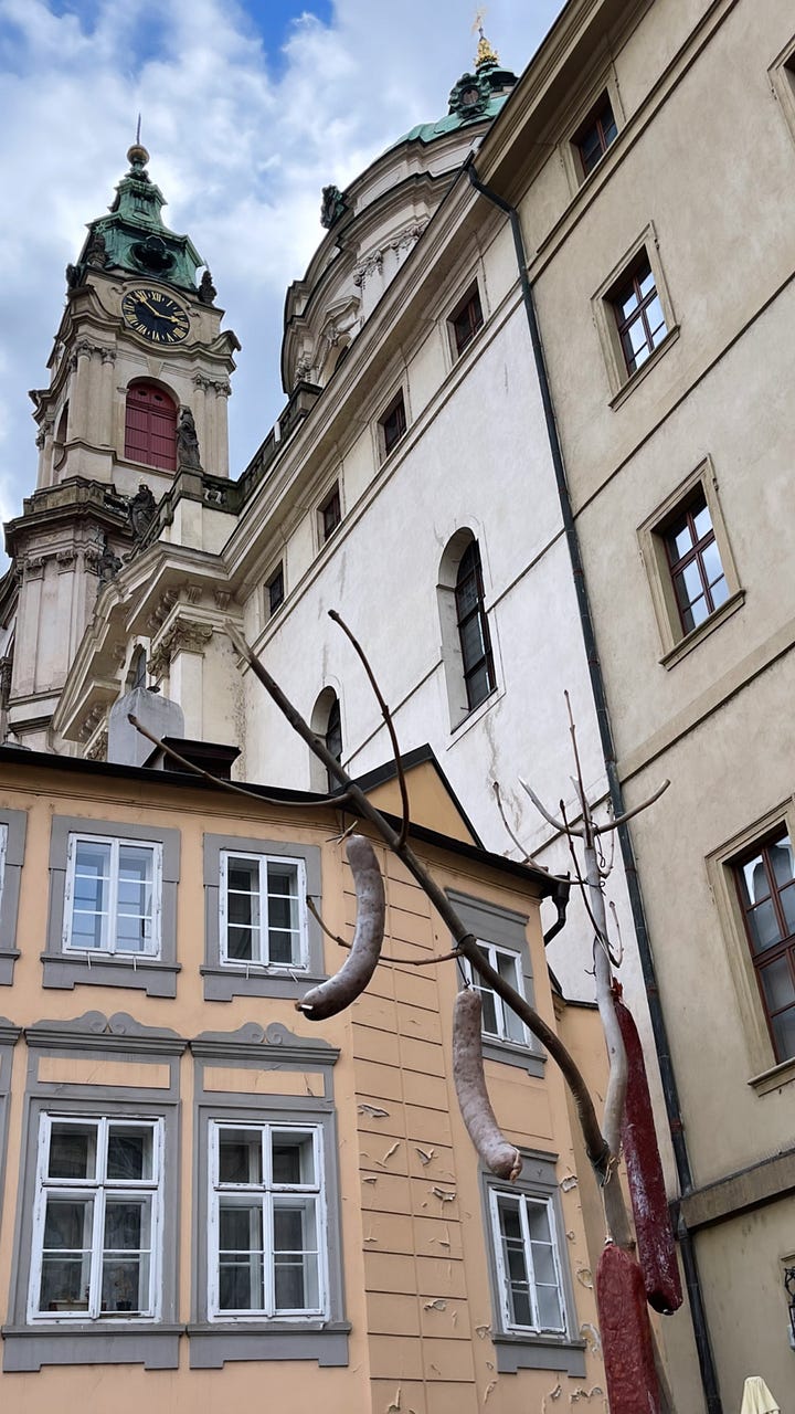 Classic Czech carnival fare — smoky sausages, golden potatoes, and roasted red peppers — the kind of hearty, unfussy food eaten standing up during Masopust celebrations.