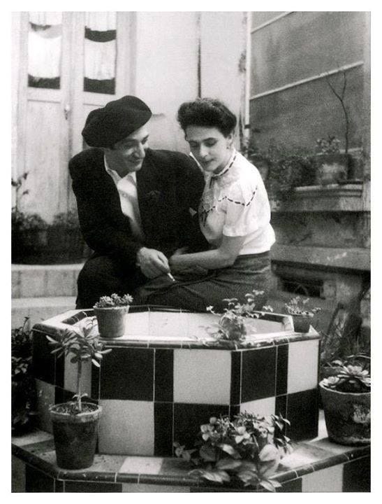 This may contain: an old photo of two people cutting into a cake