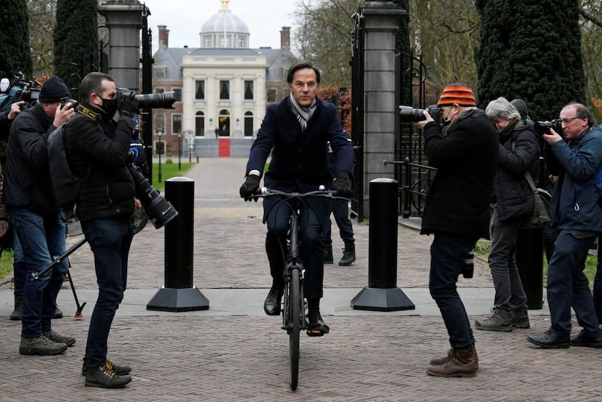A man wearing a scarf and gloves cycles through gates. A man wearing a scarf and gloves cycles through gates.
