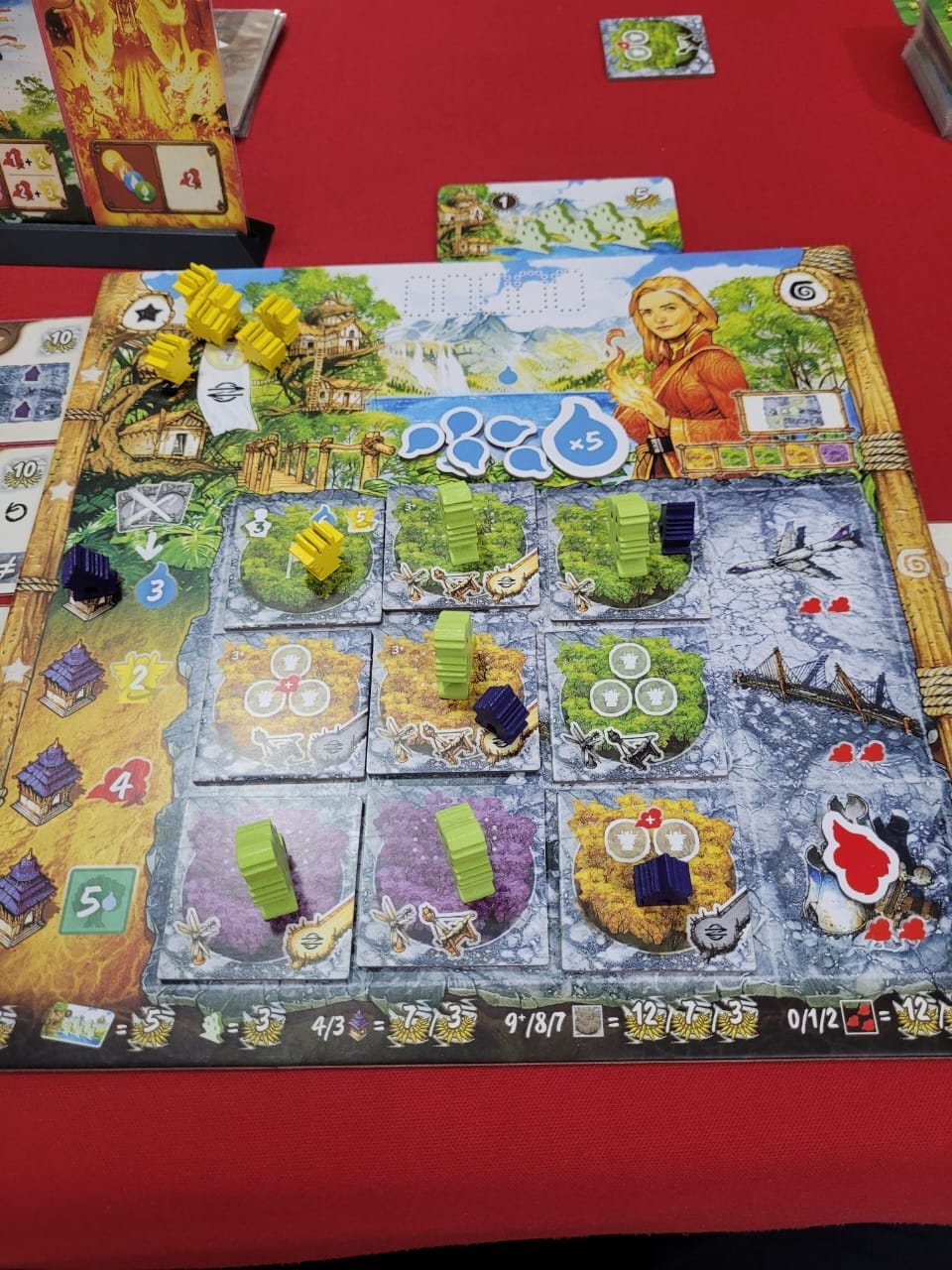 Um tabuleiro quadrado com peças amarelas, verdes e azuis espalhadas.