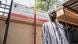 A man standing next to a sign in French that translates as: "Republic of Senegal — Departmental Council of Kedougou" A man standing next to a sign in French that translates as: "Republic of Senegal — Departmental Council of Kedougou"