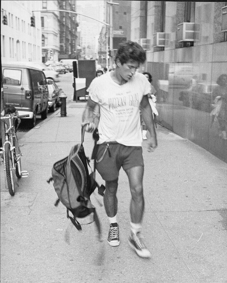 This may contain: a man walking down the street with a backpack