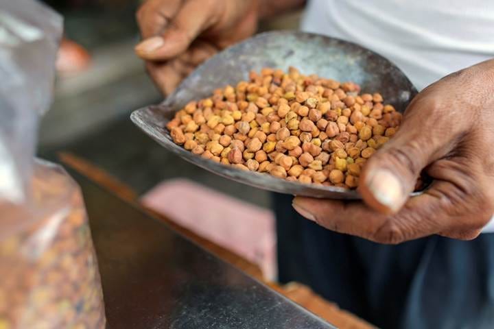 An employee holds a scoop of chickpeas in a store at a local market in Hyderabad, India.