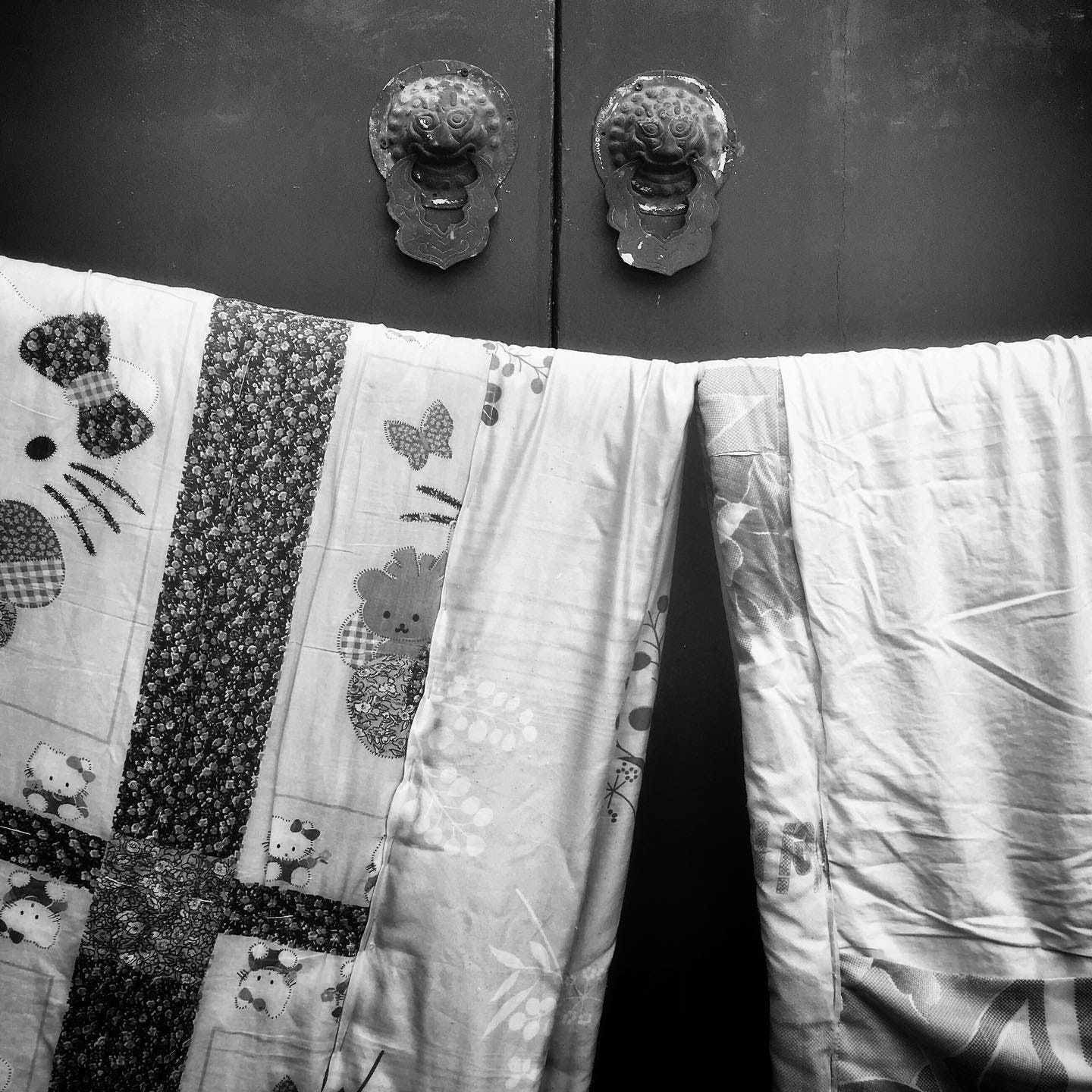 Quilts airing on a traditional door in a Beijing hutong.