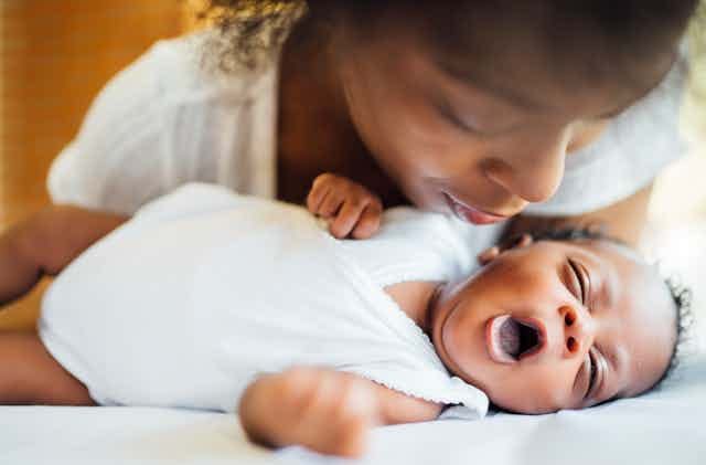 Woman bends closely over an infant