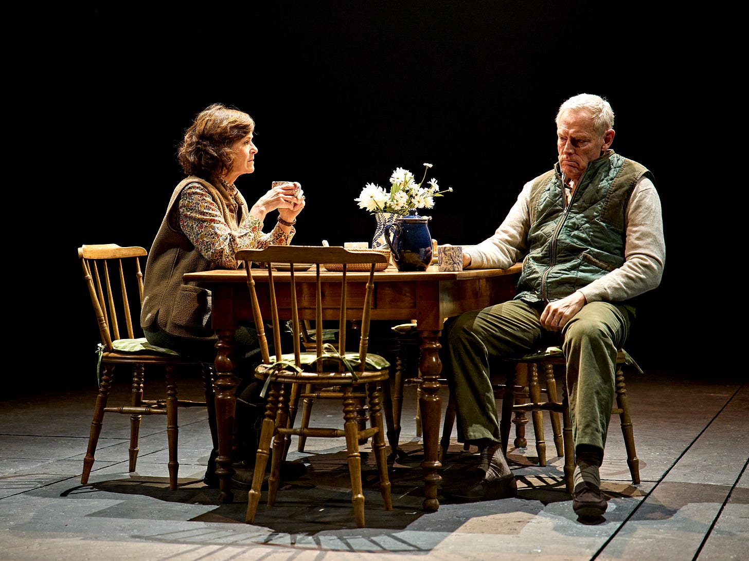 Amanda Root & Michael Simkins in Richard II, sat at a country wooden table 