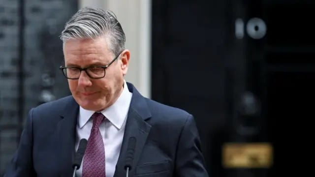 Keir Starmer is pictured speaking behind a lectern at Downing Street, wearing a suit and tie. His head his bowed as he looks down. Keir Starmer is pictured speaking behind a lectern at Downing Street, wearing a suit and tie. His head his bowed as he looks down.