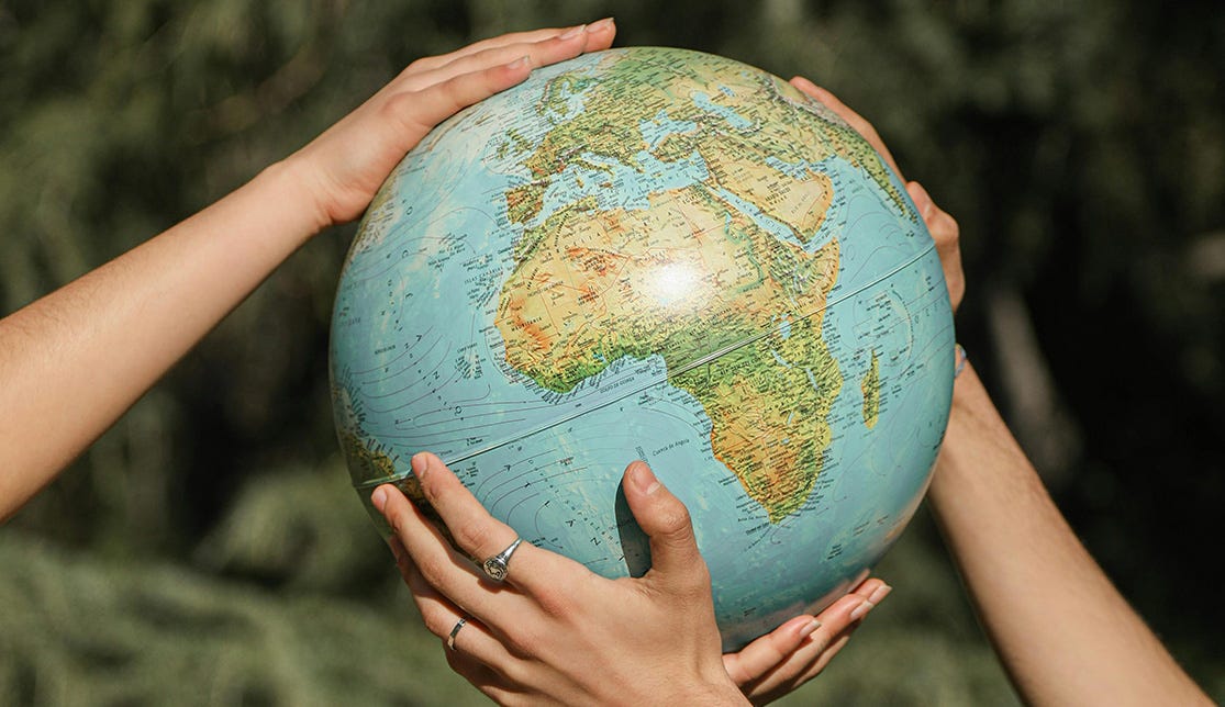 Two sets of hands holding a globe