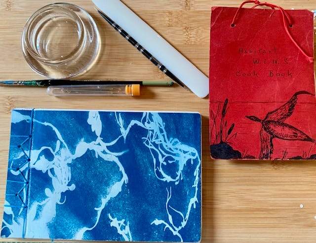 two books on a table, one is an old recipe collection, the other is a new notebook with blank pages