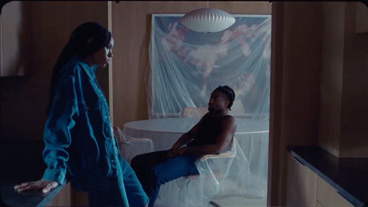 Black couple standing a part from each other in a room.