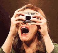 Emma Stone flashing herself in the face with a camera and crying