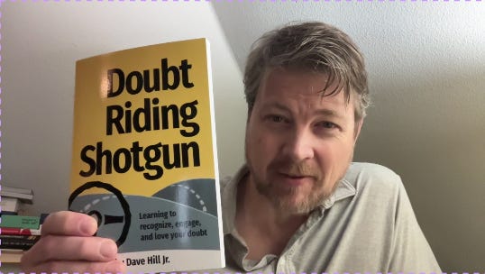 yellow book called Doubt Riding shotgun held up by author Dave Hill Jr.