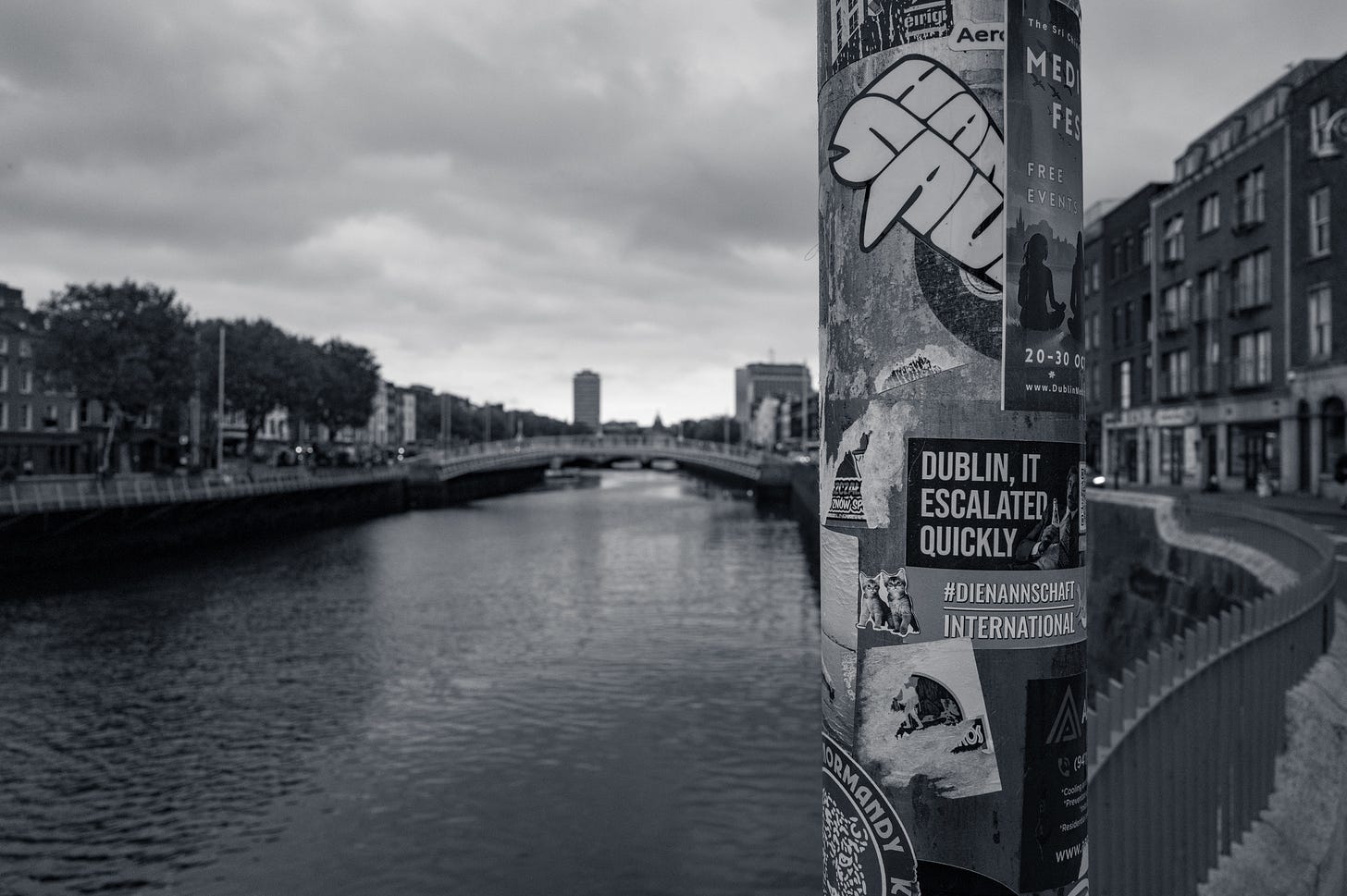 The gable ends of Dublin buildings under a heavy grey sky, in black and white, with large painted artwork across the brickwork. The gable ends of Dublin buildings under a heavy grey sky, in black and white, with large painted artwork across the brickwork.