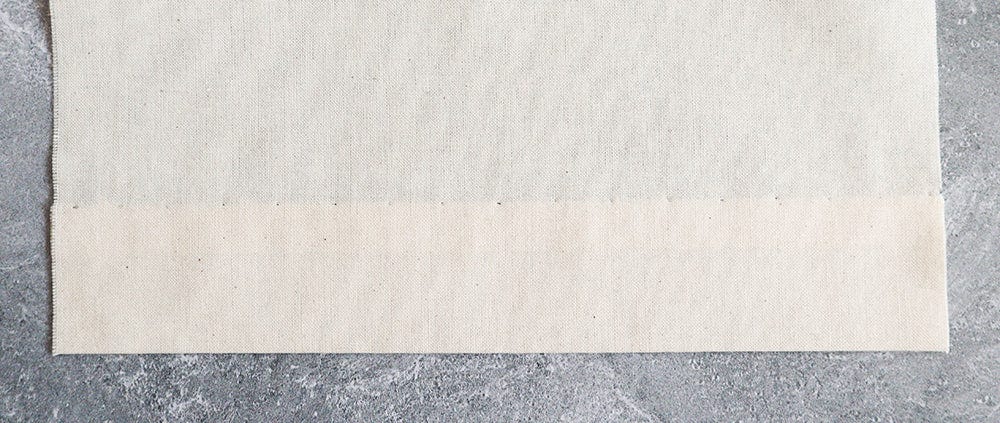 Cream muslin fabric with hem folded up and slip stitched in place.