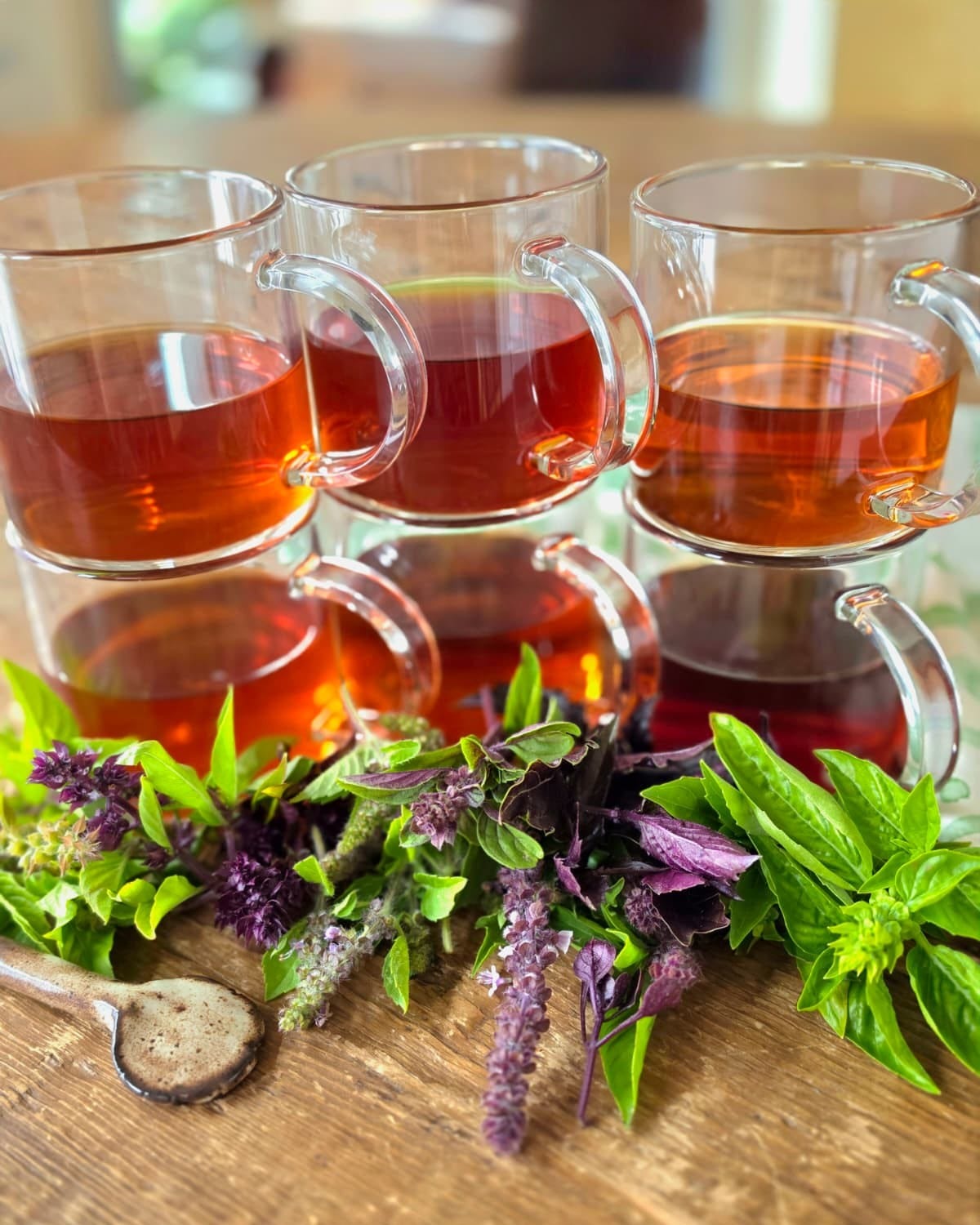 6 teacups full of tea with fresh basil leaves and a spoon in front 6 teacups full of tea with fresh basil leaves and a spoon in front