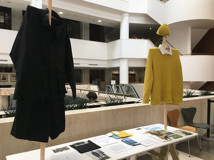 Tables and stick mannequins are layered with garments and research objects for the HERE: An Alternative Route exhibition at the British Library.