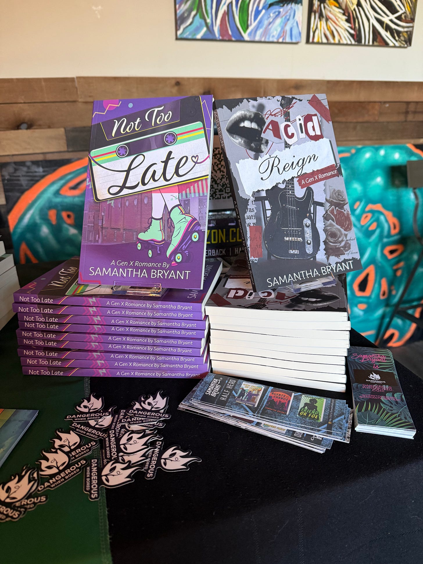 Table display of Not Too Late and Acid Reign along with some bookmarks and stickers. Table display of Not Too Late and Acid Reign along with some bookmarks and stickers.