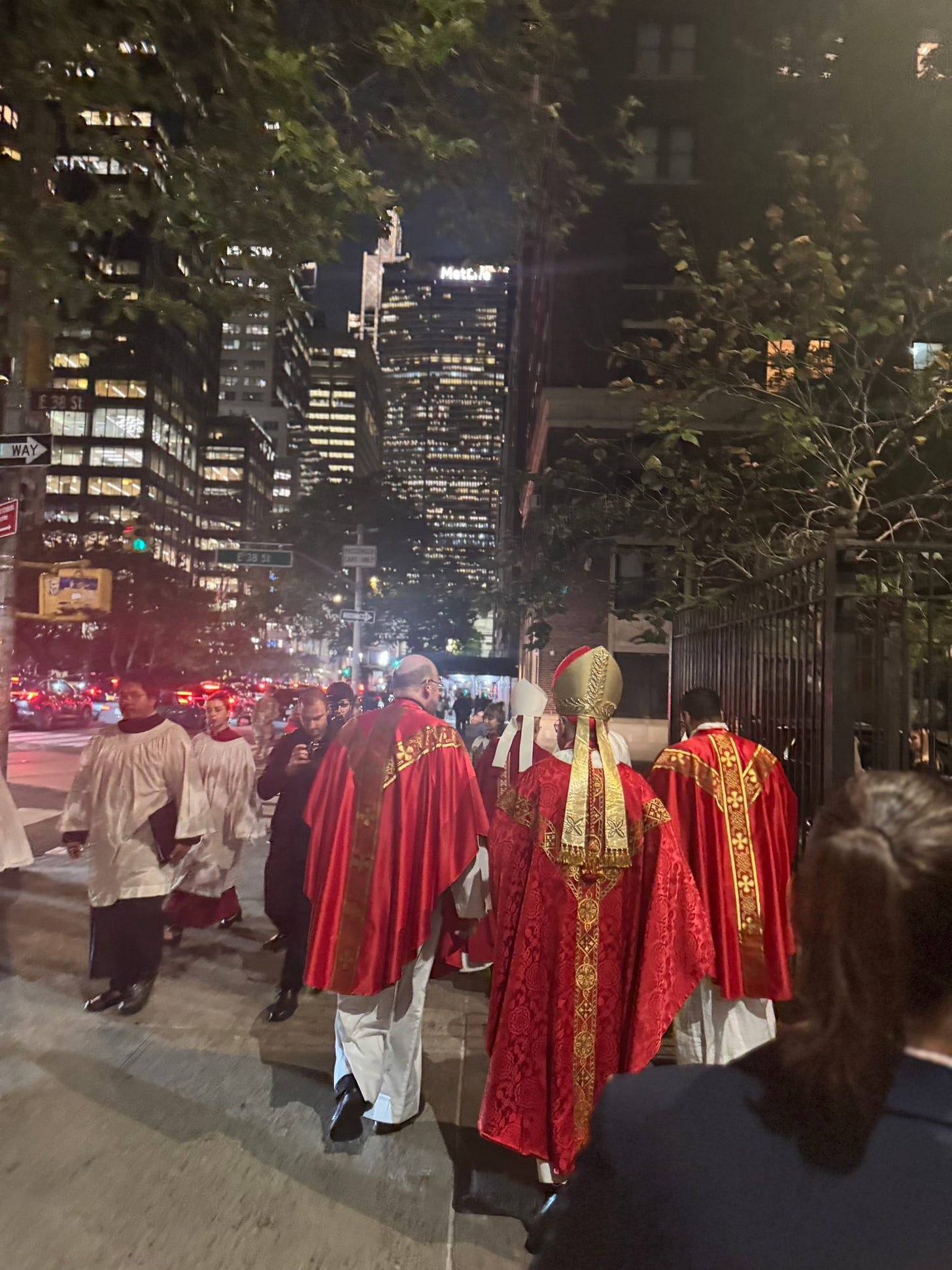 Cardinal Parolin and clergy in red vestments process along East 38th Street at night Cardinal Parolin and clergy in red vestments process along East 38th Street at night