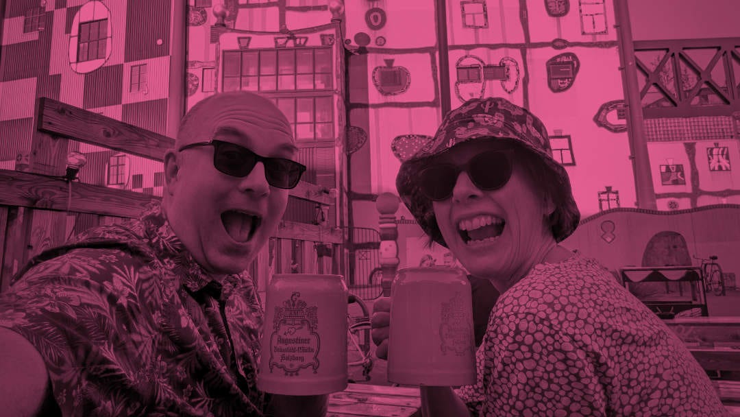 Two people gurning with mugs of beer.