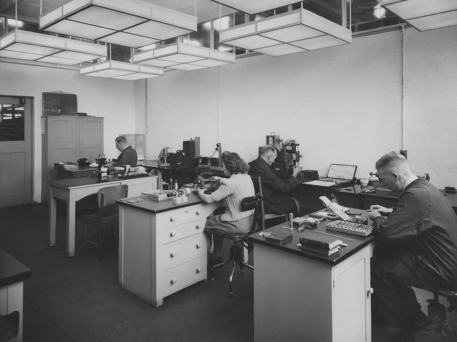 Black and white photo of people working in an office from circa 1950s.