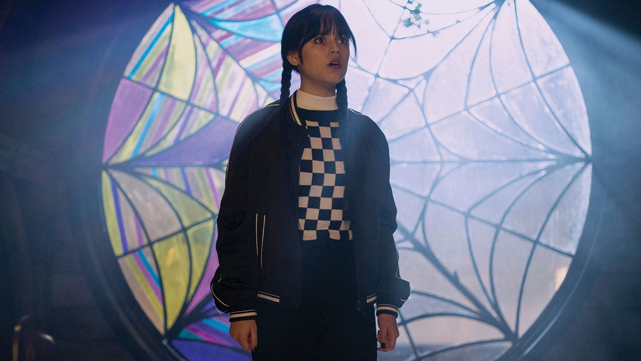 Jenna Ortega as the title character in Netflix’s Wednesday, in front of her dorm room window the colorful left side has been decorated by her roommate, Enid. Jenna Ortega as the title character in Netflix’s Wednesday, in front of her dorm room window the colorful left side has been decorated by her roommate, Enid.