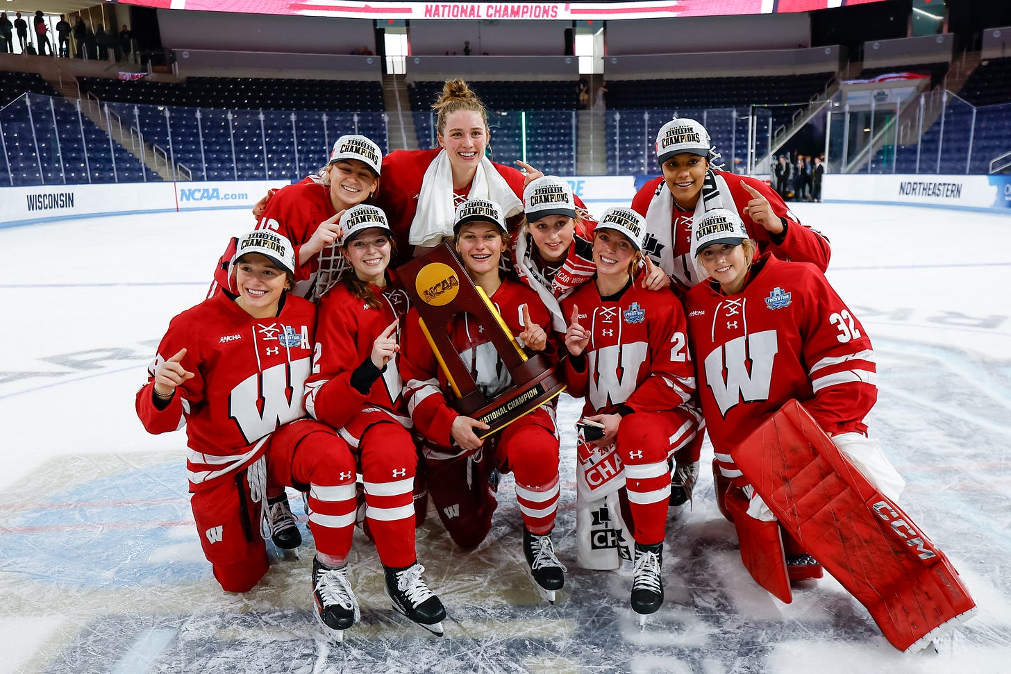 Wisconsin Badgers players pose with the national championship trophy at center ice