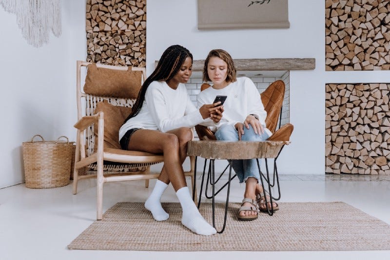 Two women look at a phone inside a gorgeous Scandinavian house. Two women look at a phone inside a gorgeous Scandinavian house.