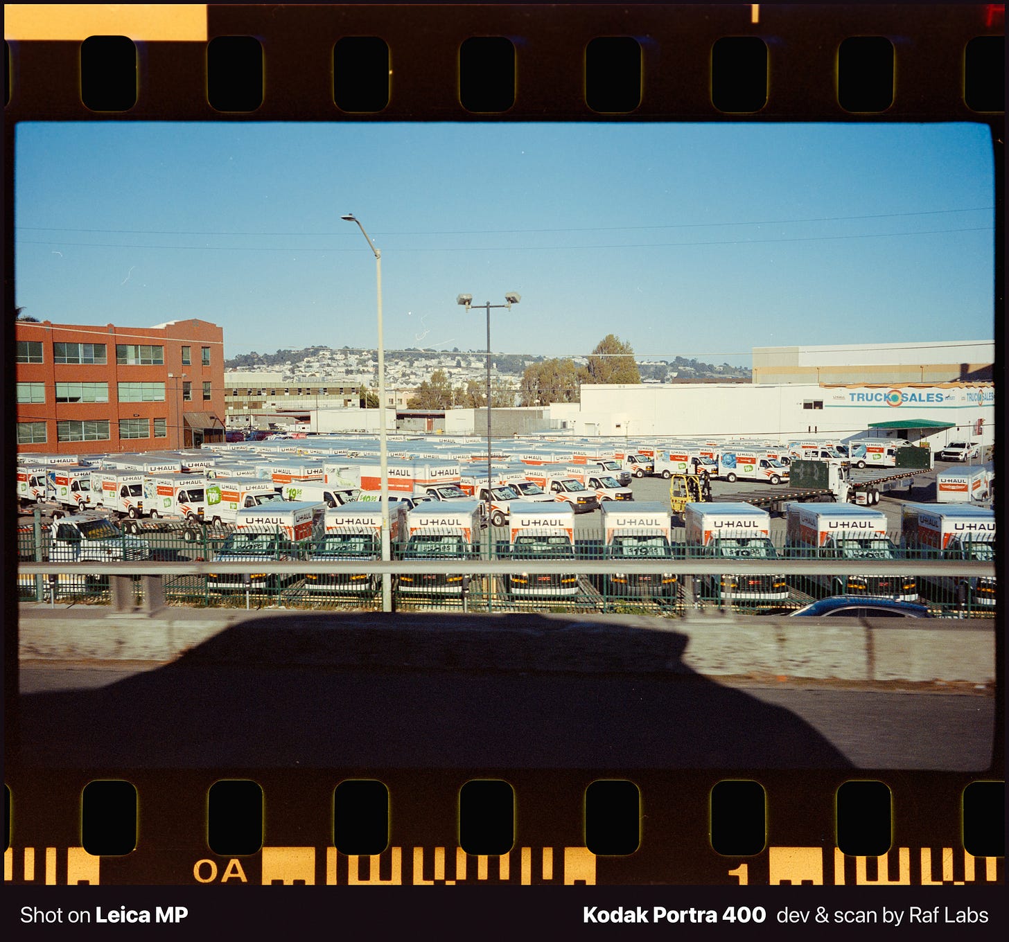 Concrete highway overpass with strong shadows under bright blue sky near San Francisco airport, analog film photography