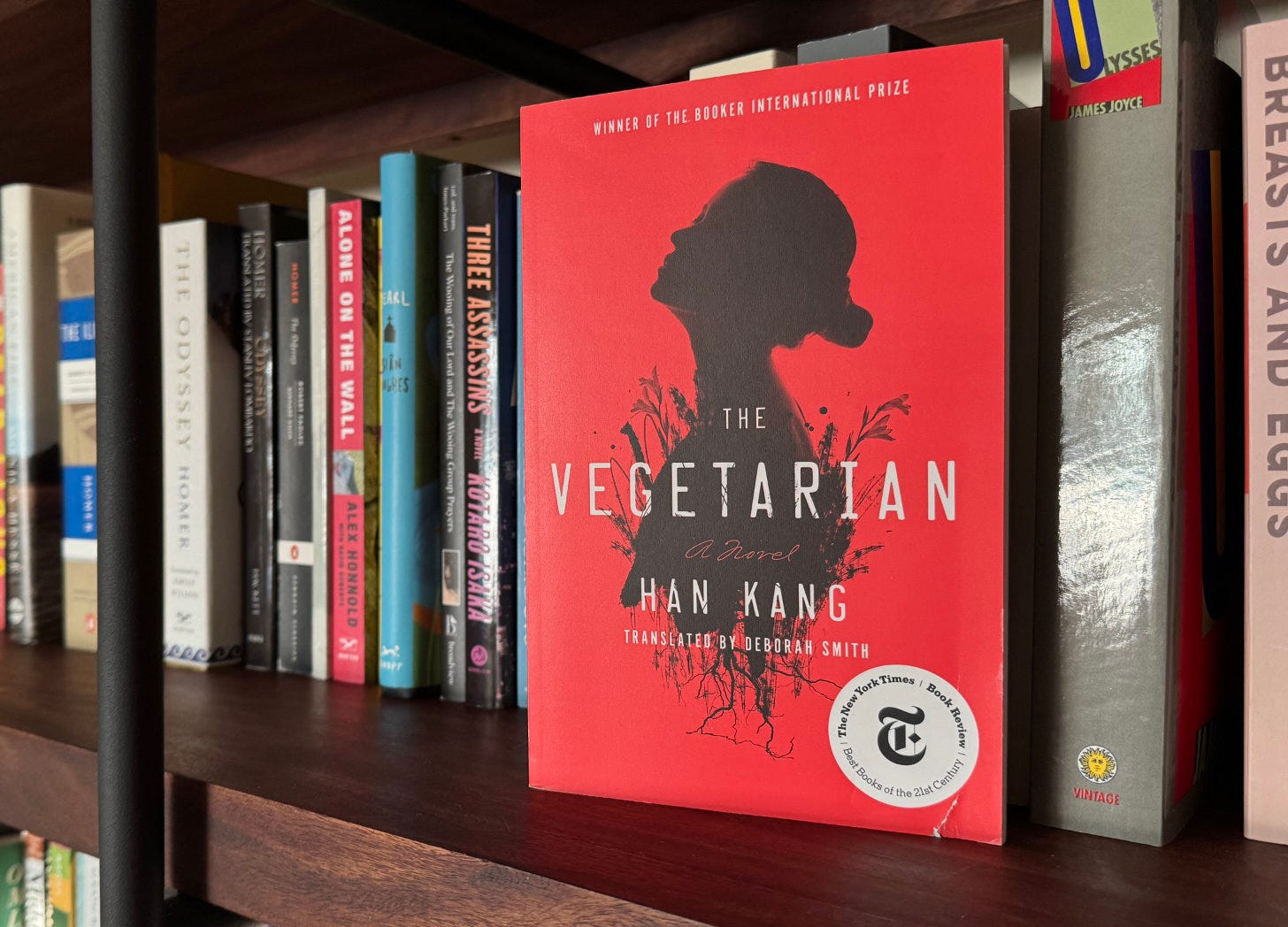 Han Kang's "The Vegetarian" is foregrounded on a full wooden bookshelf.