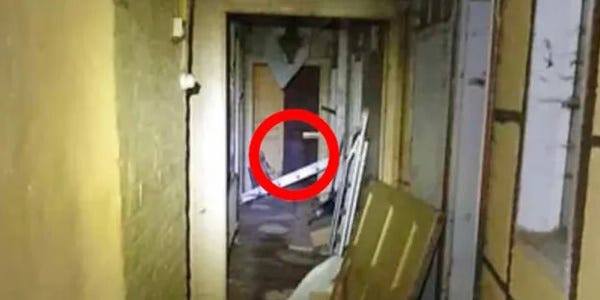 cluttered hallway with yellow walls, a doorway at the end shows some items in shot