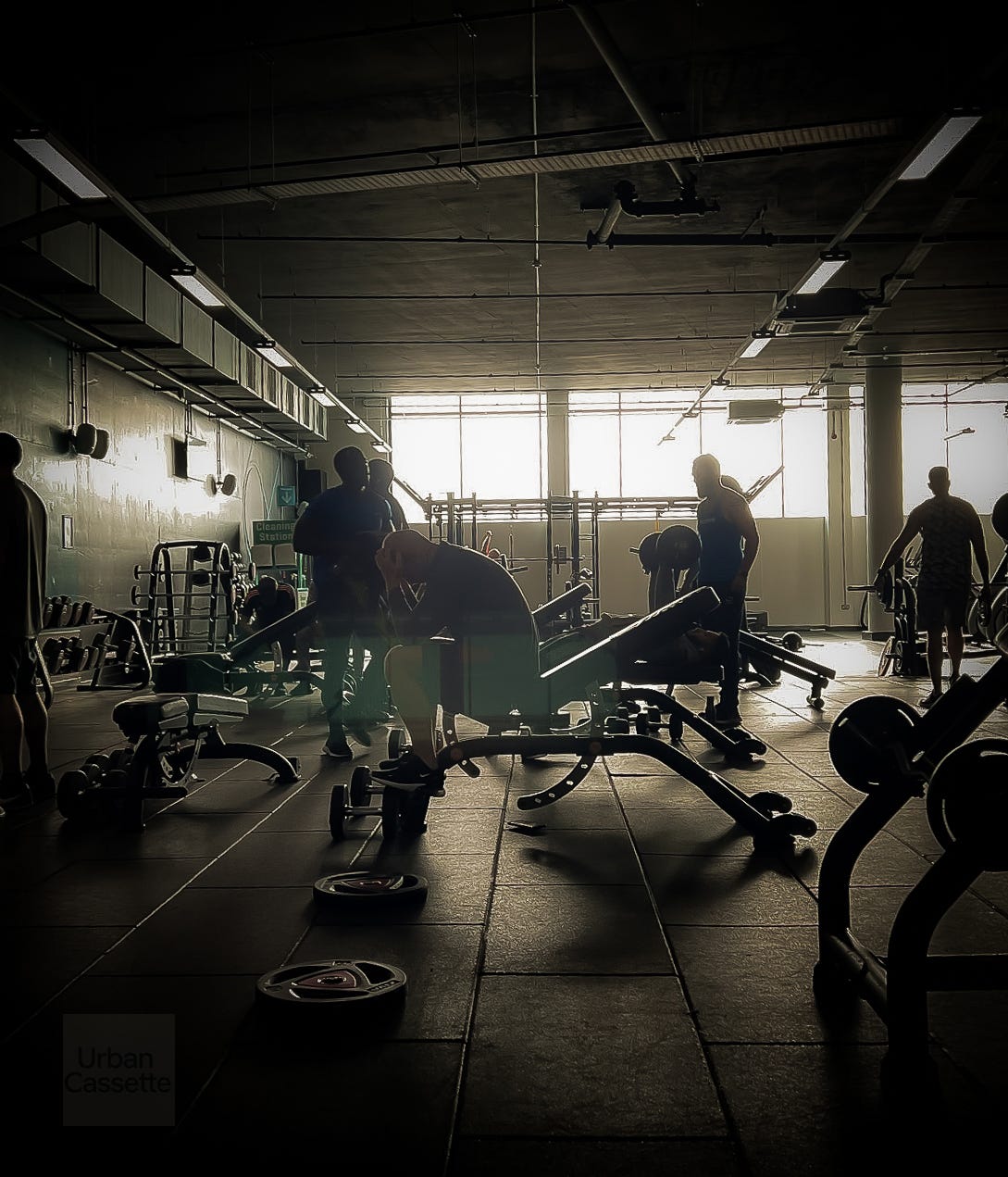 Men working out in a dim lit gym Men working out in a dim lit gym