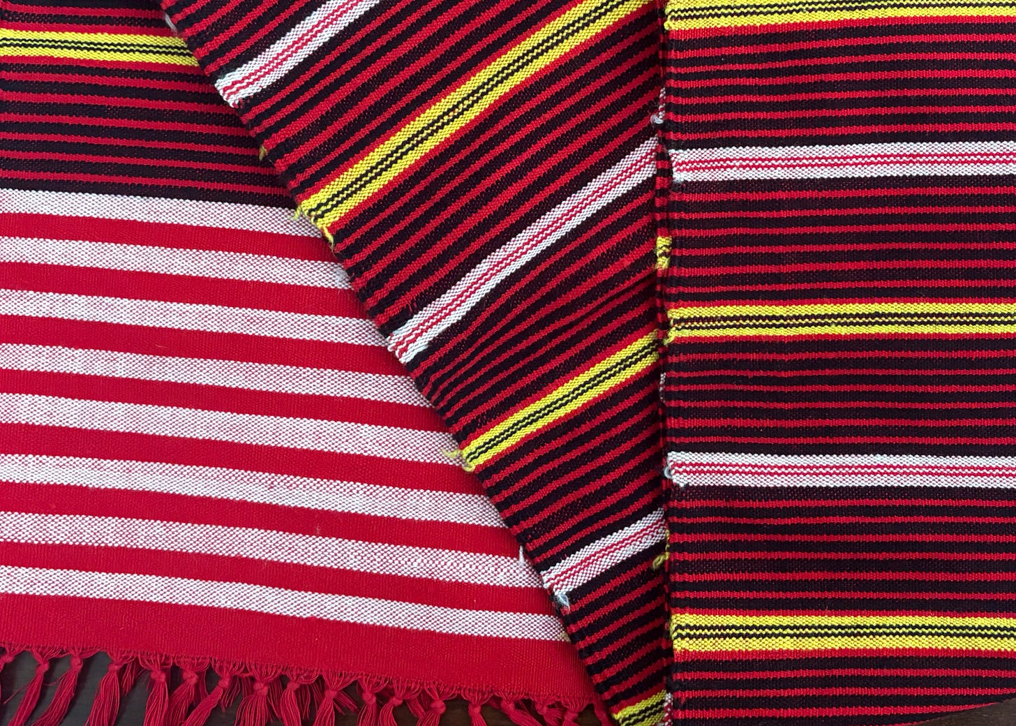 A traditional handwoven Mising E’rkok scarf from Assam featuring geometric stripes in red, black, yellow, and white. A traditional handwoven Mising E’rkok scarf from Assam featuring geometric stripes in red, black, yellow, and white.