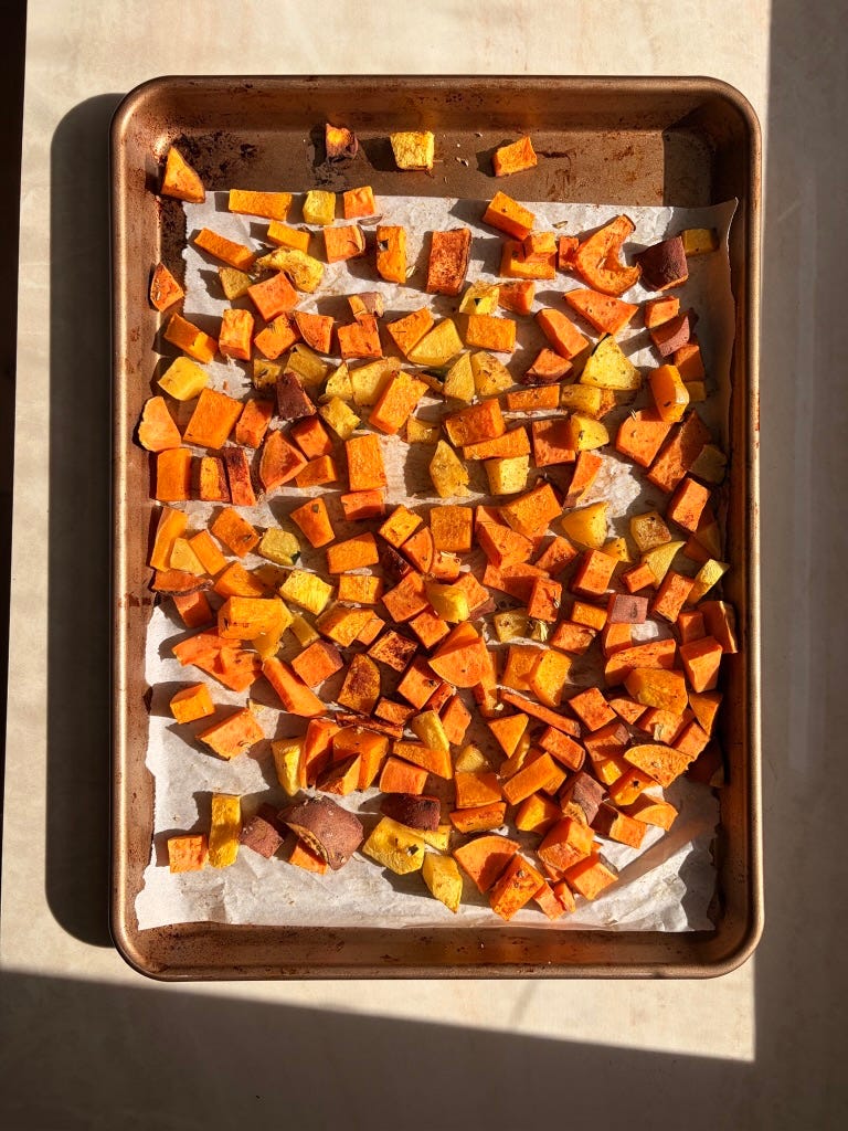 Roasted cubes of butternut squash, acorn squash, and sweet potatoes spread across a sheet pan, caramelized and lightly browned, coated in olive oil with sage and nutmeg. Roasted cubes of butternut squash, acorn squash, and sweet potatoes spread across a sheet pan, caramelized and lightly browned, coated in olive oil with sage and nutmeg.