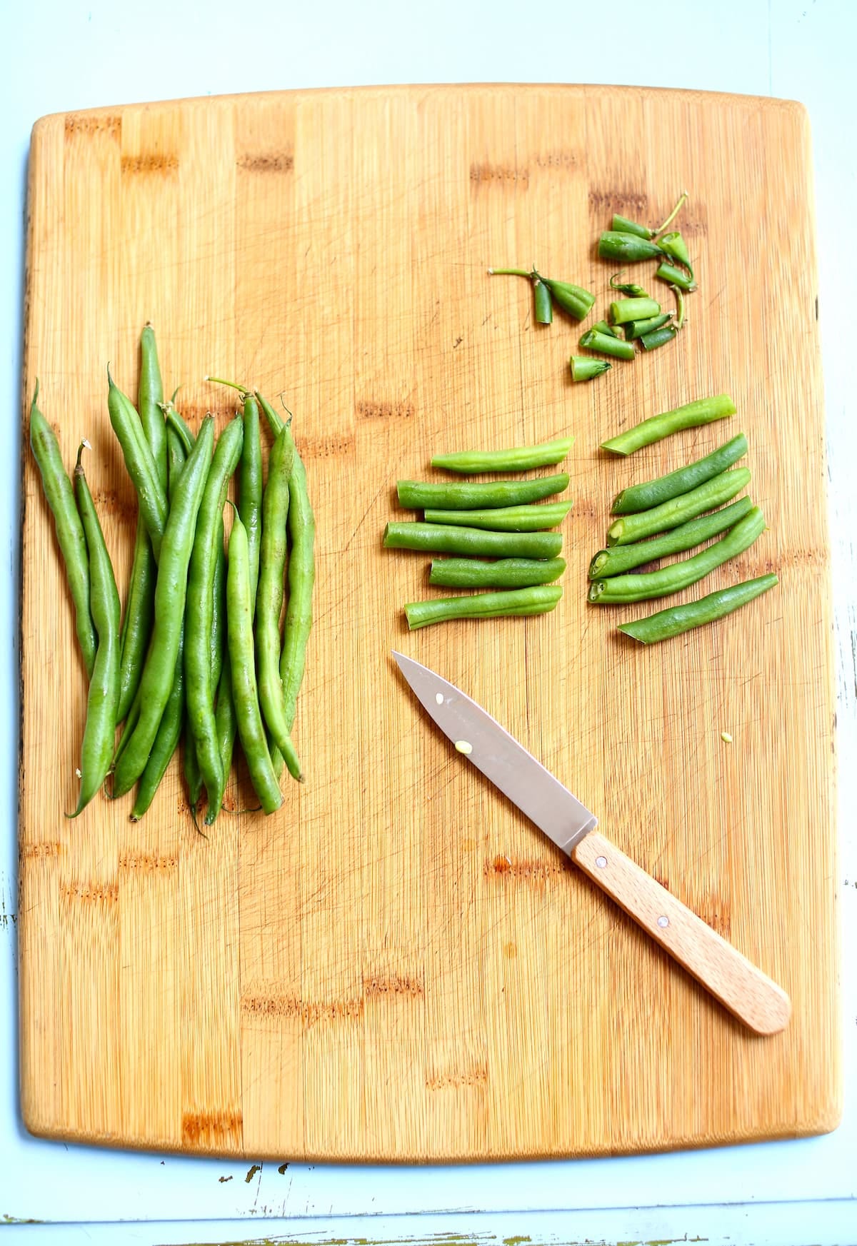 a cutting board with green beans and a knife on it.
