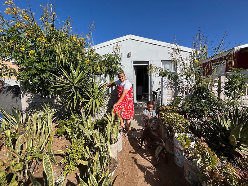 Photograph of a woman in a red dress standing in her yard.