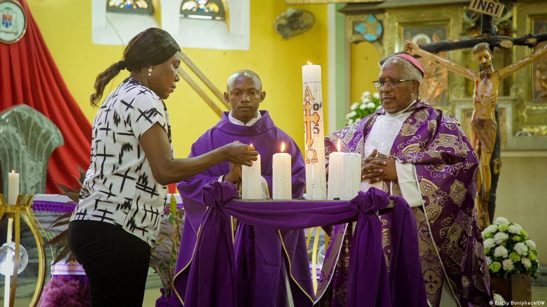A woman lights church candles as a priest and his aide look on.