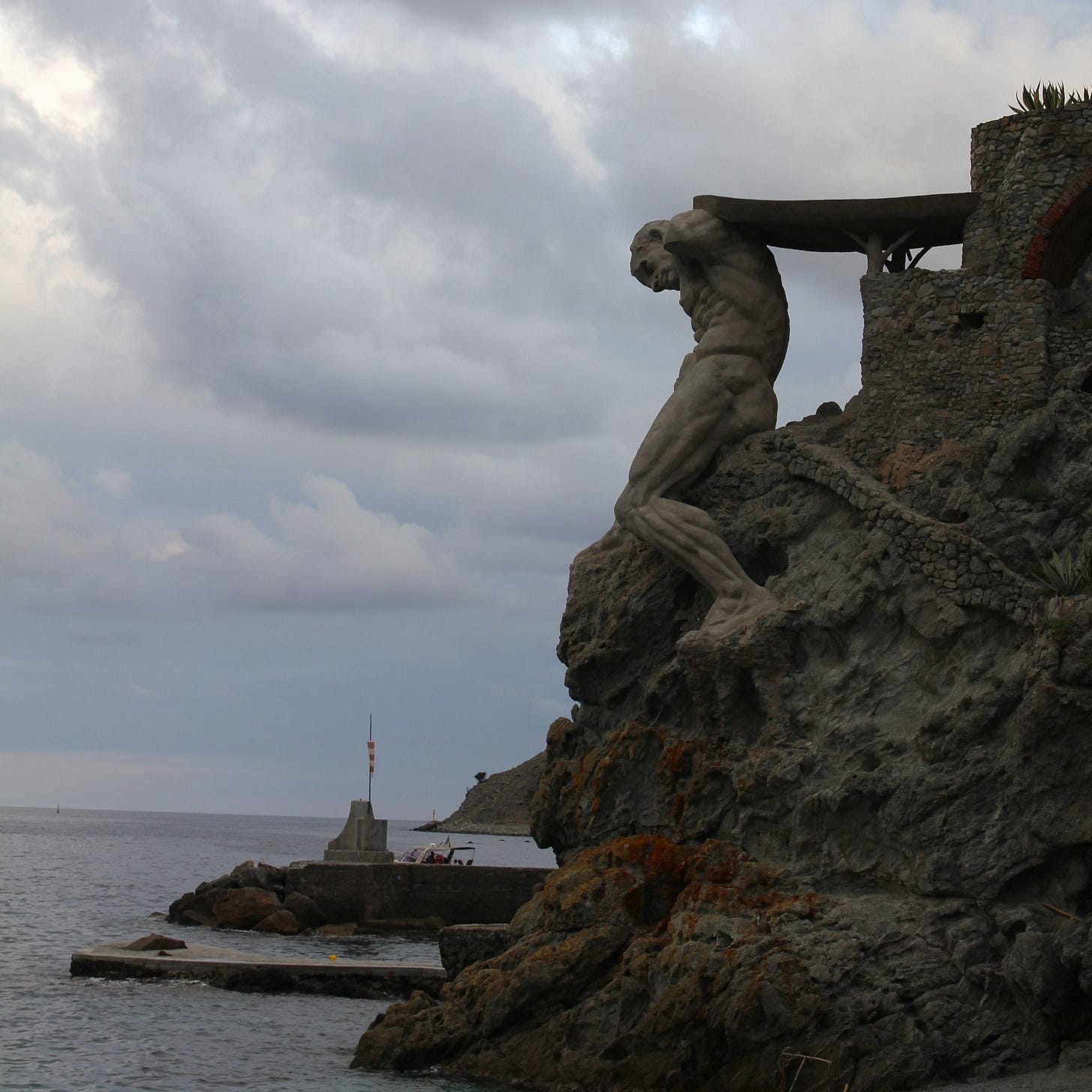 a statue of a giant made to look like it's holding up a cliff a statue of a giant made to look like it's holding up a cliff
