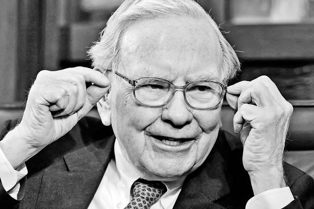 Black and white photo of Warren Buffet, mid-sentence, reaching toward the sides of his glasses