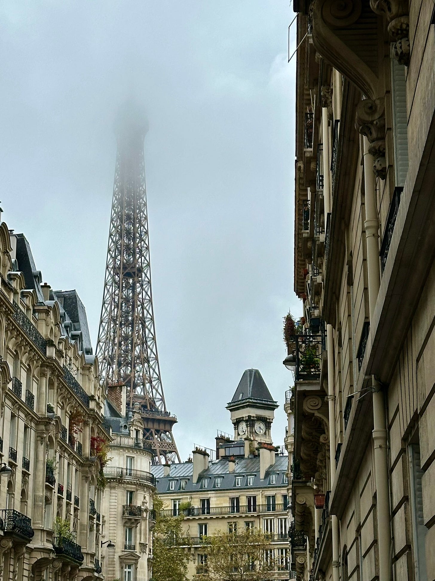 View of the Eiffel Tower through Paris streets, the top obscured by fog
