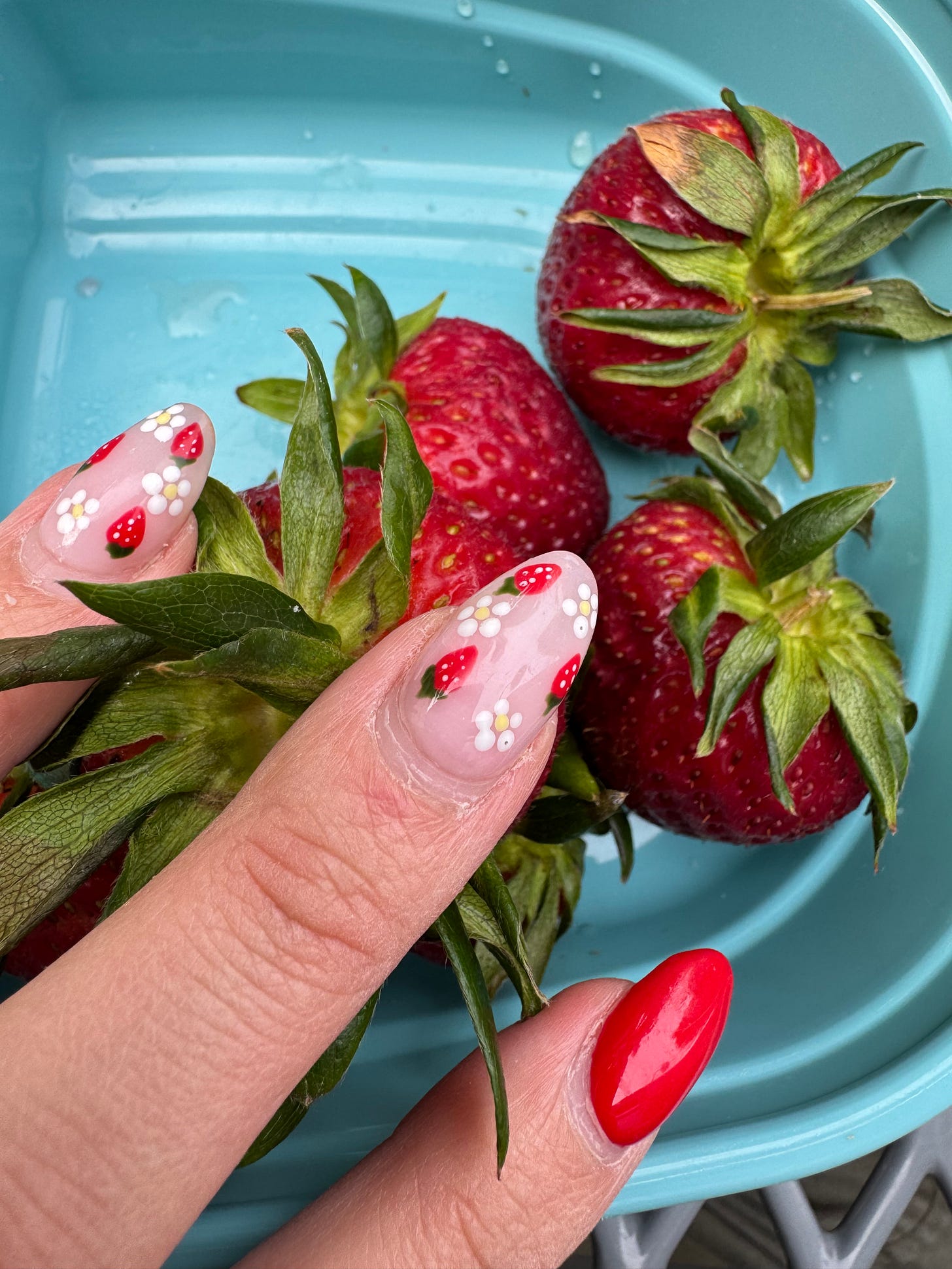 nails with a strawberry and floral design overlapping actual strawberries.