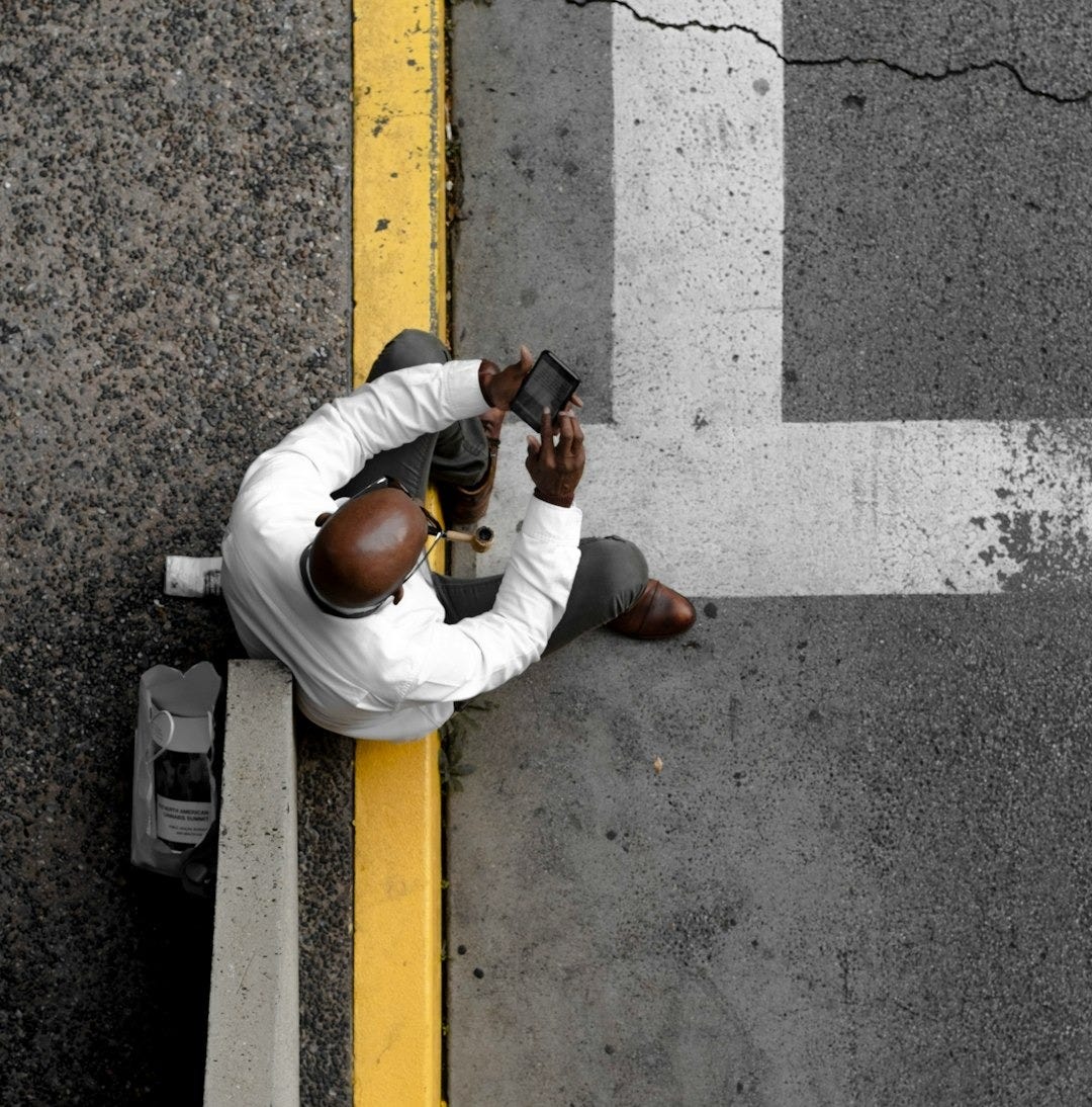 man sits on yellow painted gutter man sits on yellow painted gutter