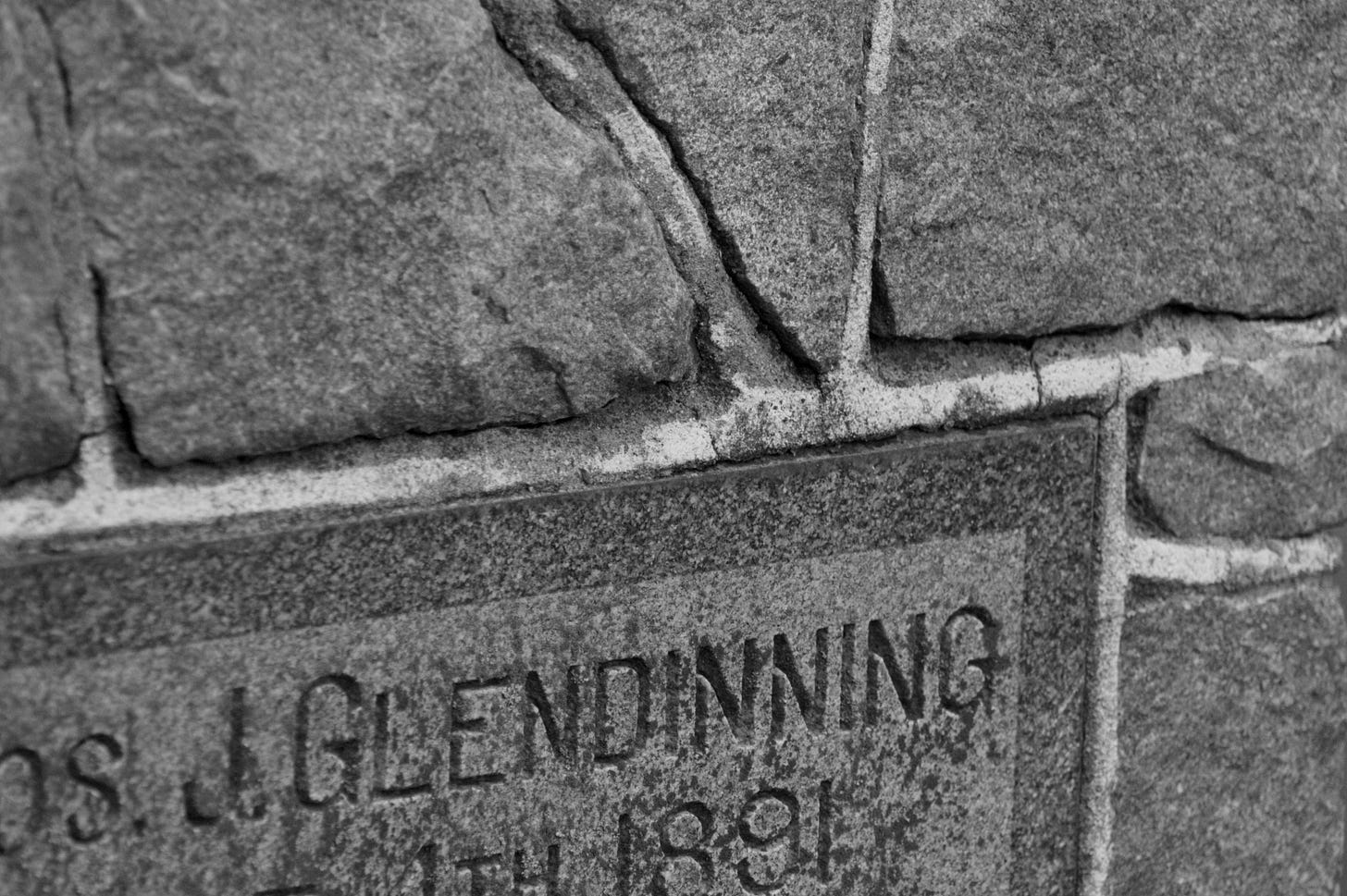 black and white photo of a grave stone, made up of stones and held together by mortar.  The last name Glendinning and the year 1891 are visible from the stone.