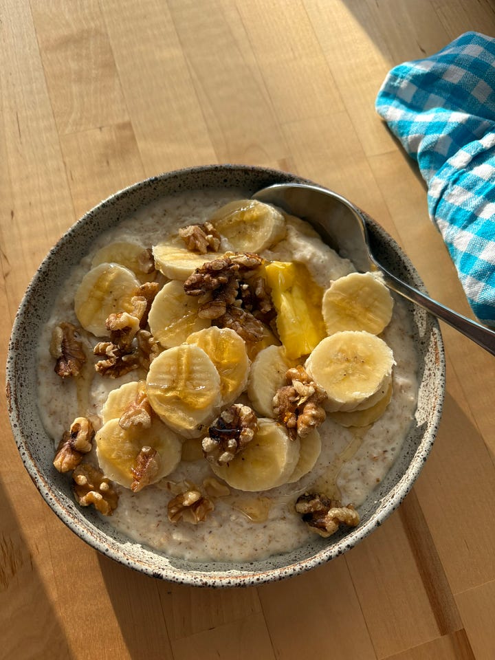 Bowl of porridge with banana, walnuts, honey and butter. A second bowl of coca porridge with banana, maple syrup and almond butter. A peppermint tea nearby.