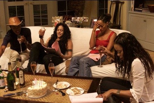 This may contain: four people sitting on a couch drinking wine and eating cake with candles in their hands