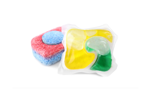 A yellow and green liquid-based dishwasher pod leans against a red and blue powder-based pod.
