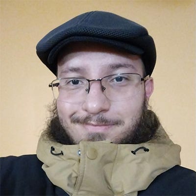 Homem branco de barba negra longa e óculos, boina escura na cabeça, vestindo casaco de frio (cor preta) com gola alta e mangas na cor bege Homem branco de barba negra longa e óculos, boina escura na cabeça, vestindo casaco de frio (cor preta) com gola alta e mangas na cor bege