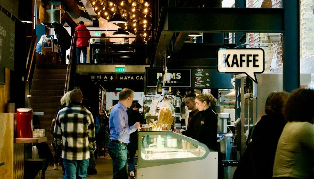 People order food and drinks in an indoor cafe.