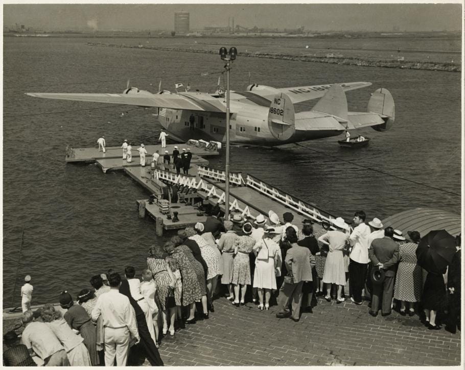 Marine Air Terminal people lined up near floating dock; flying boat in water